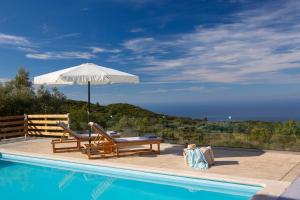 een zwembad met een parasol en twee stoelen en een tafel bij Villa Freya in Kalamitsi