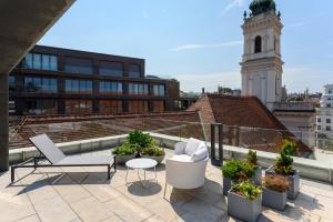 a balcony with chairs and a clock tower on a building at Emerald Hotel by Continental Group in Budapest