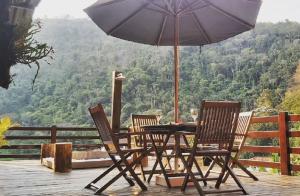 a table and chairs with an umbrella on a deck at Meu cantinho na Serra- 5 Minutos de Itaipava in Petrópolis