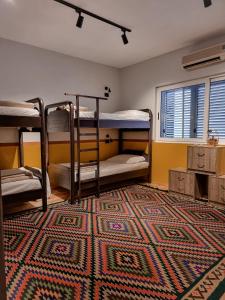 a room with three bunk beds and a rug at The Bearded Dad Hostel in Tirana