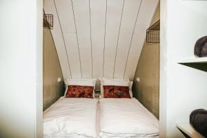 Cama en habitación pequeña con 2 almohadas en Penthouse Witsand Zeezicht, en Egmond aan Zee