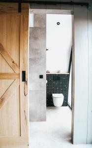 Un baño con puerta de madera y un inodoro. en Penthouse Witsand Zeezicht, en Egmond aan Zee 28 fotos más