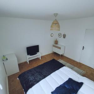 um quarto branco com uma cama e uma televisão de ecrã plano em Chambre Evasion Tout confort Saint Marceau em Orléans