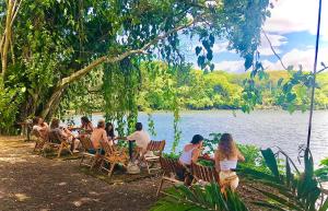 um grupo de pessoas sentadas em mesas à beira de um lago em El Pital, Chocolate Paradise em Balgue