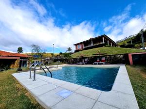 a house with a swimming pool in front of a house at Recanto Nature in Vila Verde