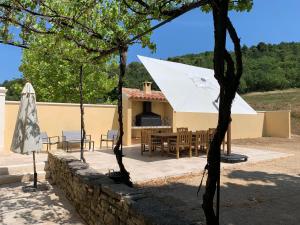 um pátio com uma mesa e um guarda-chuva branco em Gîte Tilleul - Bastide Casa mira - domaine d Esclatesang em Apt