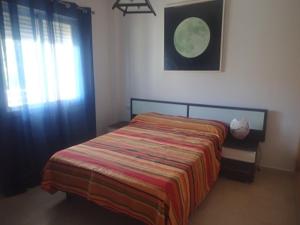 a bedroom with a bed with a colorful blanket and a window at Apartamentos Turísticos Zahazar in Zahara de los Atunes