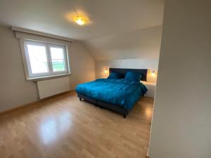 Un dormitorio con una cama azul y una ventana en 't Cappellelandhof, en Lo-Reninge