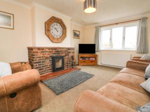 sala de estar con chimenea y reloj en la pared en Dassel Cottage, en Barnstaple