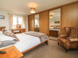 ein Schlafzimmer mit einem Bett, einem Stuhl und einem Sofa in der Unterkunft Dassel Cottage in Barnstaple