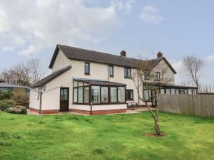 ein Haus mit großen Fenstern und einem grünen Hof in der Unterkunft Dassel Cottage in Barnstaple