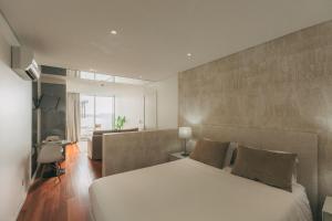 a bedroom with a large white bed and a couch at Coast Flats by Azores Villas in Ponta Delgada