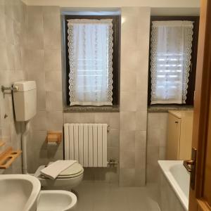 een badkamer met een toilet, een wastafel en een bad bij Appartamento Silvia in Vermiglio