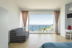Talè Gioiosa في جيويوسا ماريا: غرفة نوم مع أريكة وإطلالة على المحيط