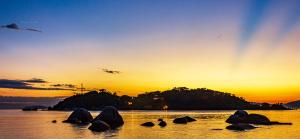 a group of rocks in the water at sunset at Pousada Casa do Oscar in Governador Celso Ramos