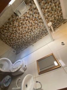 La salle de bains est pourvue de toilettes et d'un miroir. dans l'établissement Pousada Mãe Padroeira, à Aparecida