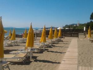 una fila di ombrelloni e sedie gialli su una spiaggia di Villetta indipendente a 50 metri dal mare a Castiglione della Pescaia