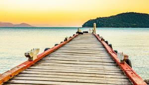 a wooden pier in the middle of a body of water at Pousada Casa do Oscar in Governador Celso Ramos