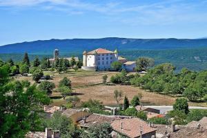 a large white building in the middle of a village at Scenic Village Home with Lake Panorama in Sainte-Croix-de-Verdon