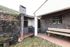 un edificio con un banco junto a una pared de piedra en holiday home, Santo Amaro, Pico, Azores en Santo Amaro