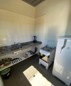 a kitchen with a stove and a white refrigerator at Chalés Recanto da Baleia in Alto Paraíso de Goiás