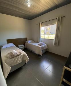 a room with two beds and a window in it at Chalés Recanto da Baleia in Alto Paraíso de Goiás