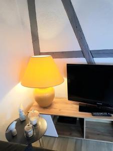 a yellow lamp sitting on a table next to a television at VUE PETITE VENISE-PLACE TO BE OLD TOWN - Parking in Colmar