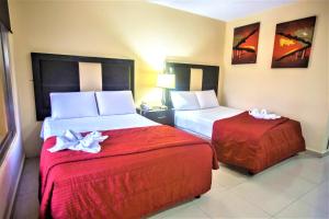a hotel room with two beds with red sheets at Hotel Plaza Mirador in M&eacute;rida