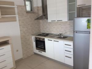 cocina con armarios blancos y nevera de acero inoxidable en Lux Apartments, en Korčula