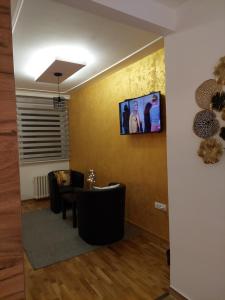 een wachtkamer met stoelen en een tv aan de muur bij Room 23 in Belgrado