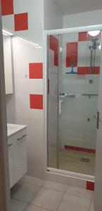 a glass shower in a bathroom with red and white walls at T3 PIEDS DANS L'EAU CLIM WIFI TERRASSE VUE MER in Banyuls-sur-Mer