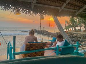 Smile Beach Home في غالي: رجل وامرأة يجلسان على الشاطئ