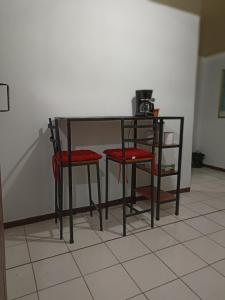阿拉胡埃拉的住宿－Departamentos Patricia，一张带两张红色椅子的黑桌,围墙旁