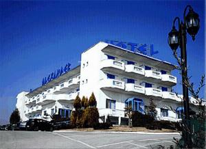 a large white building with a blue sign on it at Alexander Hotel in Serres