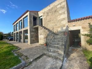 uma casa de pedra com escadas em frente a um edifício em Surribes em Braga