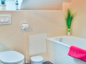 a bathroom with a white toilet and a tub and a sink at Ferienhaus Bodden in Neuendorf