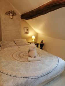 un osito de peluche sentado en una cama en un dormitorio en Jacuzzi Massage et Vin Plateau dînatoire offert, en Férolles