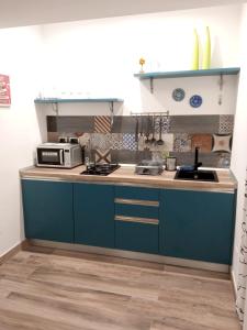 Cappuccini Express House في بوتسولي: مطبخ مع دواليب زرقاء ومغسلة