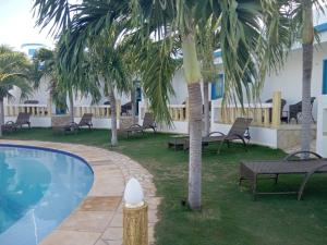 - une piscine avec des chaises et des palmiers à côté d'un bâtiment dans l'établissement Il Mondo Di Sofia, à Canoa Quebrada
