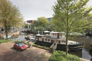 a red car parked next to a boat in a river at Houseboat Volle Maan in Amsterdam