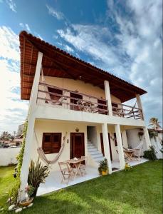 a white house with tables and chairs in a yard at Suíte das flores em Guajiru in Trairi