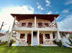 a white house with chairs and a balcony at Suíte das flores em Guajiru in Trairi