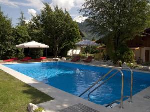 a blue swimming pool with chairs and an umbrella at Gästehaus Gamsei - Bosch Hermann in Grassau