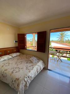 a bedroom with a bed and two windows and a patio at Suíte das flores em Guajiru in Trairi