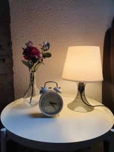 una mesa con una lámpara y un reloj y un jarrón con flores en Schöne 3 1/2 Zimmer Wohnung in der Zentralschweiz, 