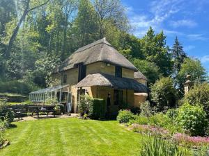 謝伯恩的住宿－Round Lodge Dorset，庭院中带茅草屋顶的大房子
