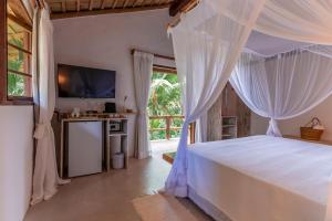 a bedroom with a bed with white curtains and a window at DA GRAÇA HOTEL in Trancoso +142 photos