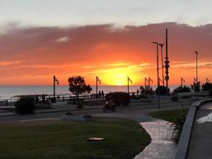 una puesta de sol sobre el océano con una persona en moto en Cabañas Sendero de Pinos - Alquileres RV en Monte Hermoso