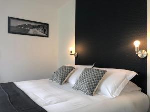 a bedroom with a white bed with two pillows at Le Rocher Appart Hôtel in Valognes