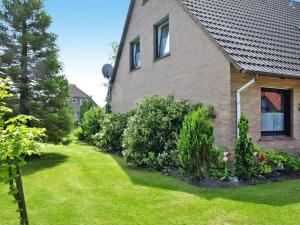 ein Haus mit einem Garten mit grünem Gras und Büschen in der Unterkunft Terraced house, Nessmersiel in Neßmersiel
